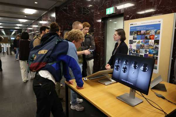 Besucher und Labormitarbeiterin am Ausstellungsstand Fluiddynamik