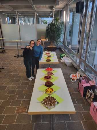 Zwei junge Frauen stehen lachend vor einem Kuchenbuffet