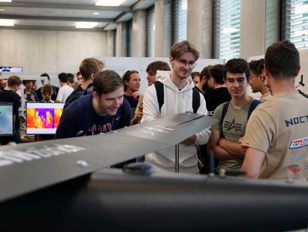 Vergrösserte Ansicht: Besucher neben der Drohne im Gespräch mit dem Team