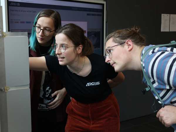 Vergrösserte Ansicht: Studierende demonstriert Besuchern einen neuartigen Käfig für Labormäuse