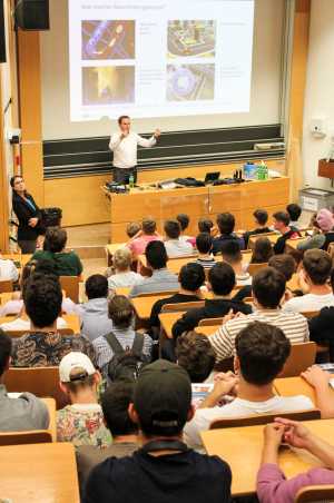 Professor André Bardow mit erhobenen Händen beim Präsentieren vor vollem Hörsaal.