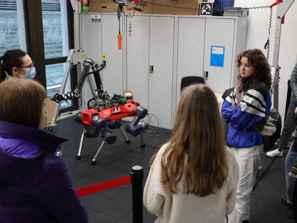 Schoolgirls look at robot Anymal