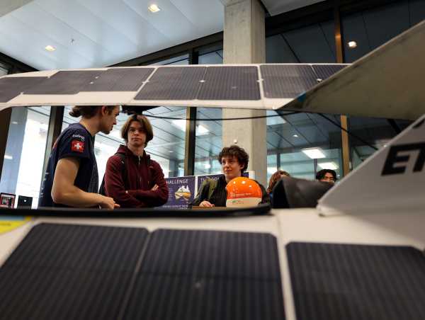 Enlarged view: Student explains the technology to visitors, view through solar panel