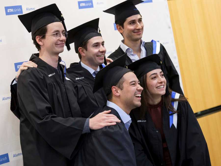 Group of graduates posing for a group picture with talar hats and gowns.