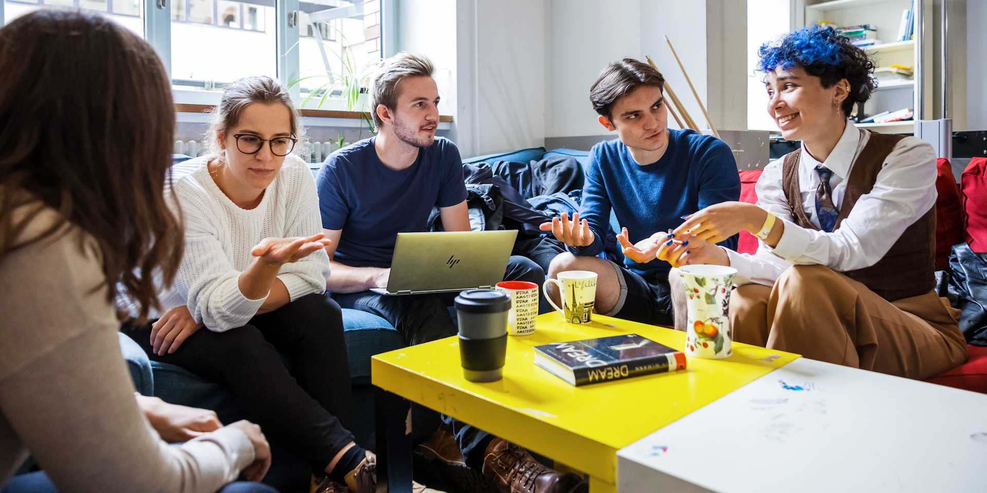 Male and female students sitting around a coffee table chatting.